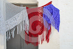 Colorful woolen knitted shawls drying outdoors.