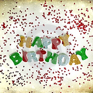 The colorful words HAPPY BIRTHDAY made from multicolored glitter letters on a white background with confetti