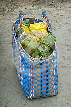 Colorful woven basket, shopping bag filled with groceries wrapped in banana leaves. Southeast Asia.