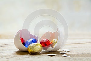 Colorful wrapped chocolate eggs in a white chicken eggshell on a