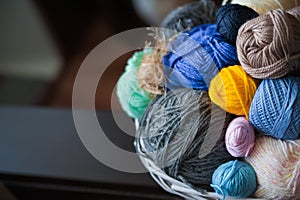 Colorful yarn balls in wicker basket on white
