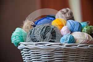 Colorful yarn balls in wicker basket on white