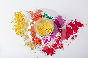 Colorful yellow holi powder in a glass bowl on white background and multicolored holi powder around it