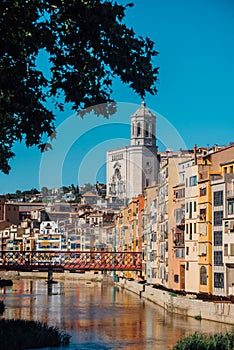 Colorful yellow and orange houses and bridge Pont de Sant Agusti reflected in water river Onyar, in Girona, Catalonia, Spain