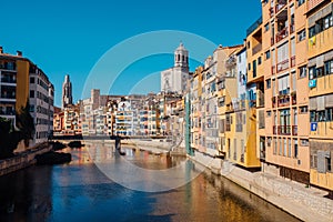 Colorful yellow and orange houses and bridge Pont de Sant Agusti reflected in water river Onyar, in Girona, Catalonia, Spain