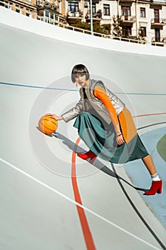 Colorful young lady playing basketball wearing glamourous outfit