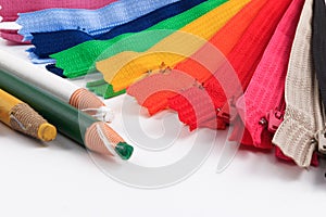 Colorful zippers and pencils white background.