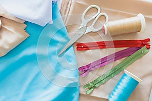 Colorful Zips scissors and spools of thread lay on fabrics textile cloth for Tailor equipment decoration concept