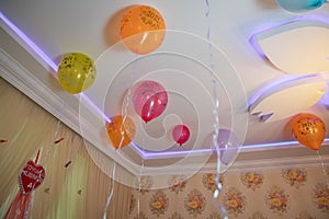 Colorfull balloons float on the white ceiling in the room for the party. Wedding or children birthday party decoration