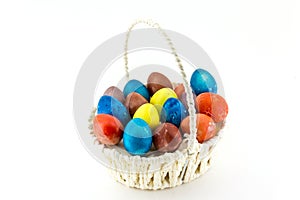 Colorfull Easter eggs in wicker basket isolated on white background