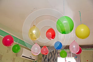 Colorfull and red balloons float on the white ceiling in the room for the party. Wedding or children birthday party decoration