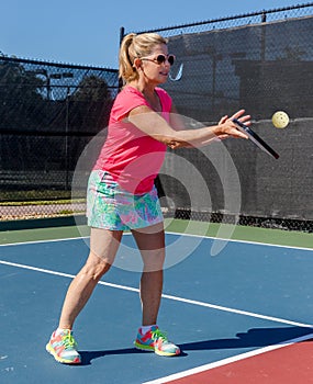 Colorfully dressed pickleball player with her eye on the ball