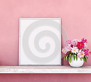 Colorfully flowers with empty white picture frame on pink wall background