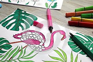 Coloring page with children drawing and set of felt tip pens on wooden table, closeup