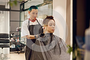 Colorist dyes hair of woman with brush and foil in beauty salon. Professional hair care products