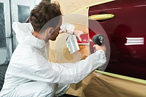 Colorist man compare color sample with car paint using special lamp.