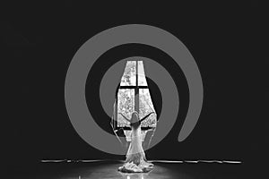 Colorless, black and white photography - the bride stands with her back to the camera and opens the curtains in a large room