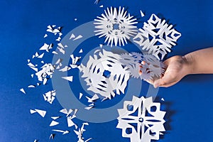 Background of various Christmas themed snowflakes cut out of white paper on a trendy blue background 2020 with a gift