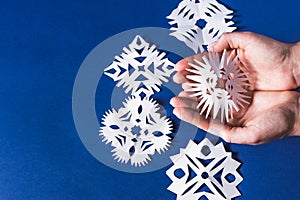 Background of various Christmas themed snowflakes cut out of white paper on a trendy blue background 2020 with a gift