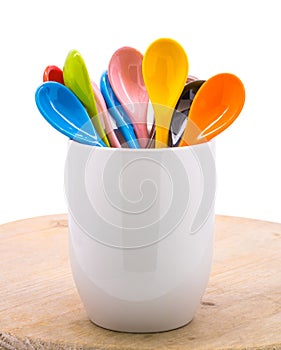 Colors ceramics spoon in mug on wooden backdrops. Colorful concept