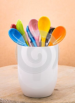 Colors ceramics spoon in mug on wooden backdrops. Colorful concept