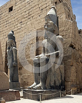 Colossal seated statue and a standing statue of Rameses II at the 1st Pylon, the main entrance for  the Luxor Temple.