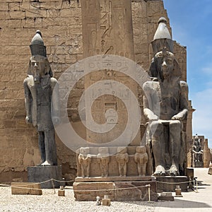 Colossal seated statue and a standing statue of Rameses II at the 1st Pylon, the main entrance for  the Luxor Temple.