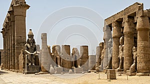 Colossal statue of seated Ramesses II and standing statues between papyrus-bud columns in the Ramesses II Court, Luxor Temple.