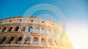 Colosseum or Coliseum ancient ruins background blue sky Rome, Italy, view from below, stone arches and sunrays