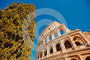 Colosseum or Coliseum ancient ruins background blue sky Rome, Italy, view from below, stone arches and sunrays