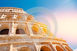 Colosseum or Coliseum ancient ruins background blue sky Rome, Italy, view from below, stone arches and sunrays