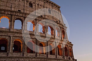 Colosseum, Rome, Italy. The outer wall of the evening coliseum. Arched openings are highlighted in orange backlighting.