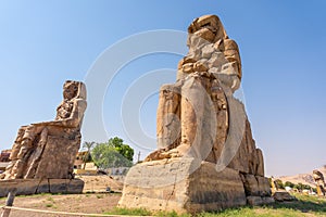 Colossi of Memnon statues under the sunlight and a blue sky in Luxor, Egypt