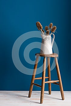 Colour Card and Vase on a Stool Over Blue Backdrop