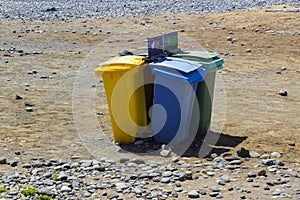 Colour coded rubbishe bins for re-cycling waste on a sunny beach in Teneriffe in Playa Las Americas in the Spanish Canary islands