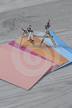 Colour paint swatch cards with miniature scale model painters and decorators on a grey wood background