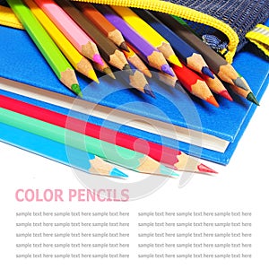 Colour pencils and a blue note book isolated on white