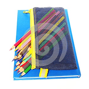 Colour pencils and a blue note book isolated on white background