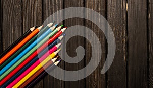 Colour pencils lids on wooden dark table background with banner copy space