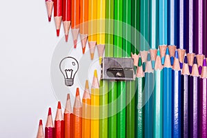 Colour pencils organized in the shape of a zipper opening up to a light bulb as a symbol of creativity