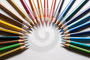 Colour pencils on white wood background close up. Circular arrangementn
