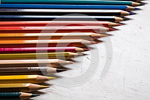Colour pencils on white wood background close up. Half screen arrangementn