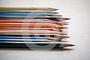 Colour pencils on white wood background close up. Horizontal arrangementn