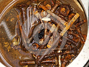 Colour Photo of Rusted Nuts and Bolts in a Tin of Water