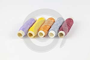 Coloured bobbins of thread on white background