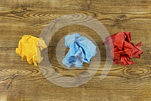Coloured crumpled paper balls on wood. Creativity crisis concept. Set of crumpled yellow, blue and red paper balls.