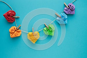 Coloured hearts hung on rope with wooden clips on a blue background. Copy space. Valentine`s Day concept. LGTB gay concept