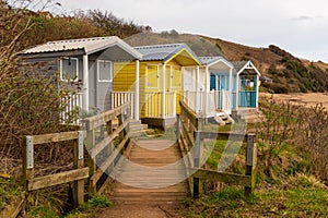 Coloured huts above a beach with boadwalk for access