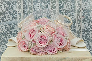 A coloured macro photo of a detailed bouquet with pink roses, white small flowers and a fake diamond in the centre of the roses