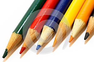 Coloured pencils in colours green, red, blue, yellow, orange and black, aligned side by side in a closeup macro photo isolated